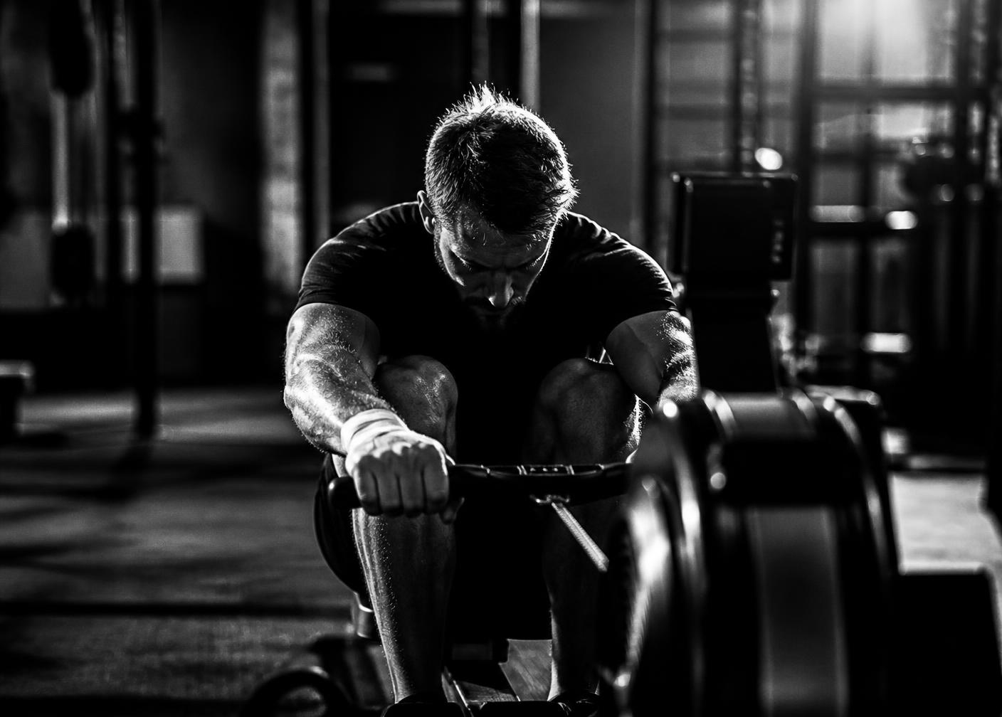 A hybrid athlete head-down mid-stroke on a rowing erg in a functional fitness gym